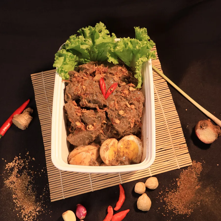 Lapis Daging Signature — daging sapi berbumbu gelap disajikan di atas anyaman bambu